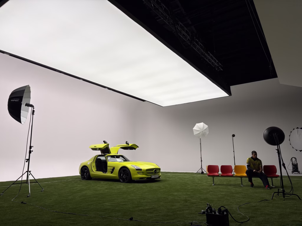 Gelber Mercedes-Benz SLS mit geöffneten Flügeltüren im Studio, darüber die durchgehende SkyLed-Softbox
