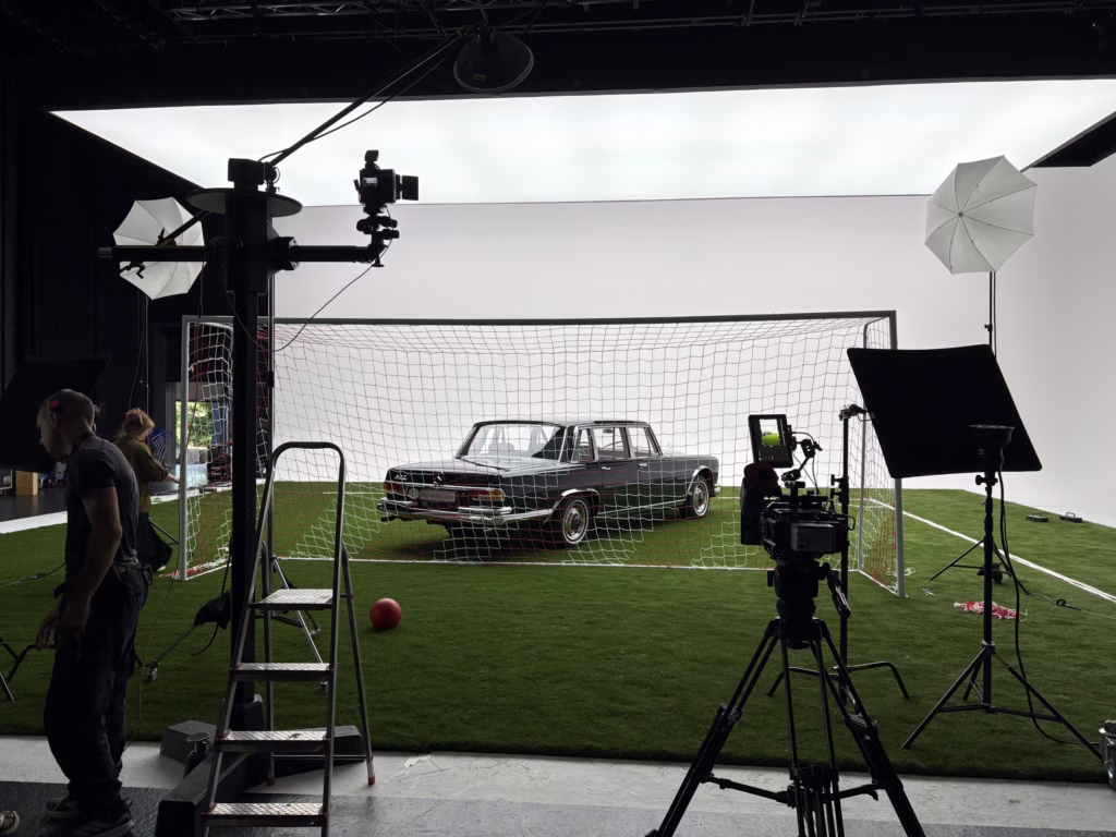 Setaufbau mit Kamerakran vor einem Fußballtor, dahinter eine Limousine unter der beleuchteten Fläche